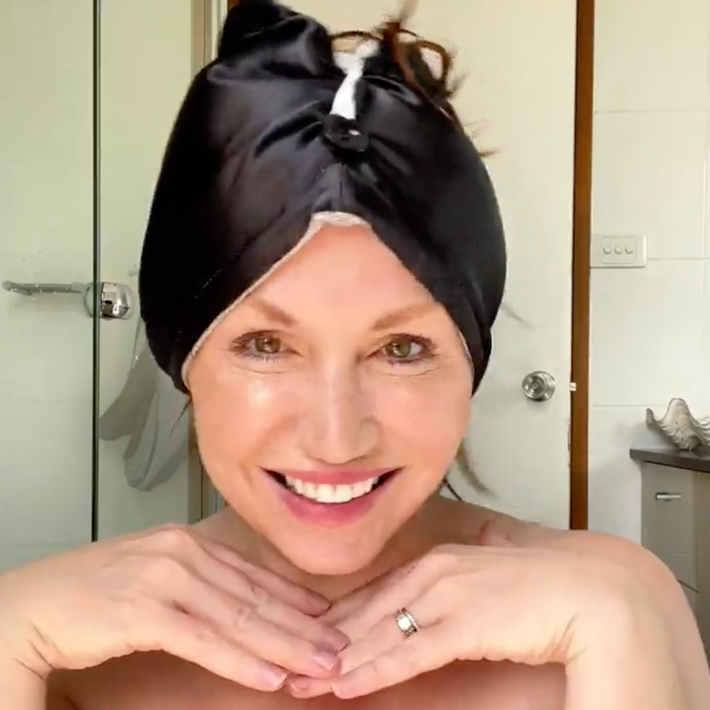 Woman with a black towel wrapped around her head in a bathroom setting